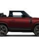 A red Land Rover Defender with a convertible roof.